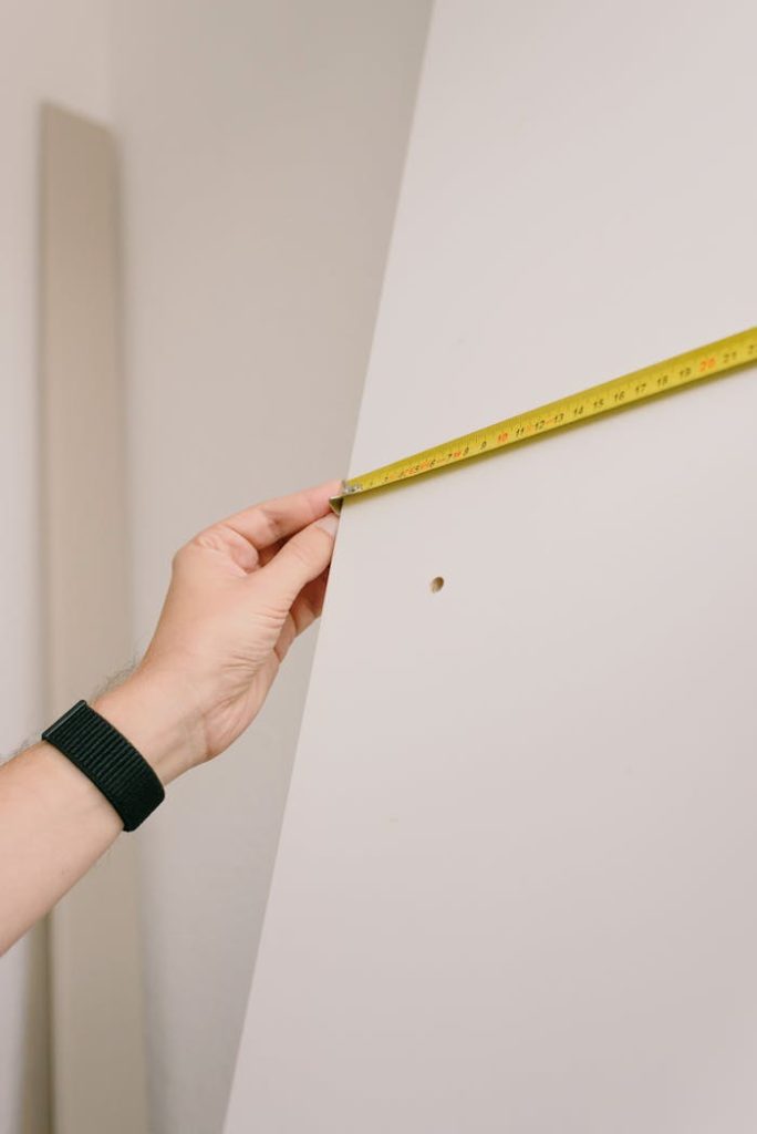 Close-up of a person measuring a wall with a yellow tape measure, perfect for home renovation or construction themes.